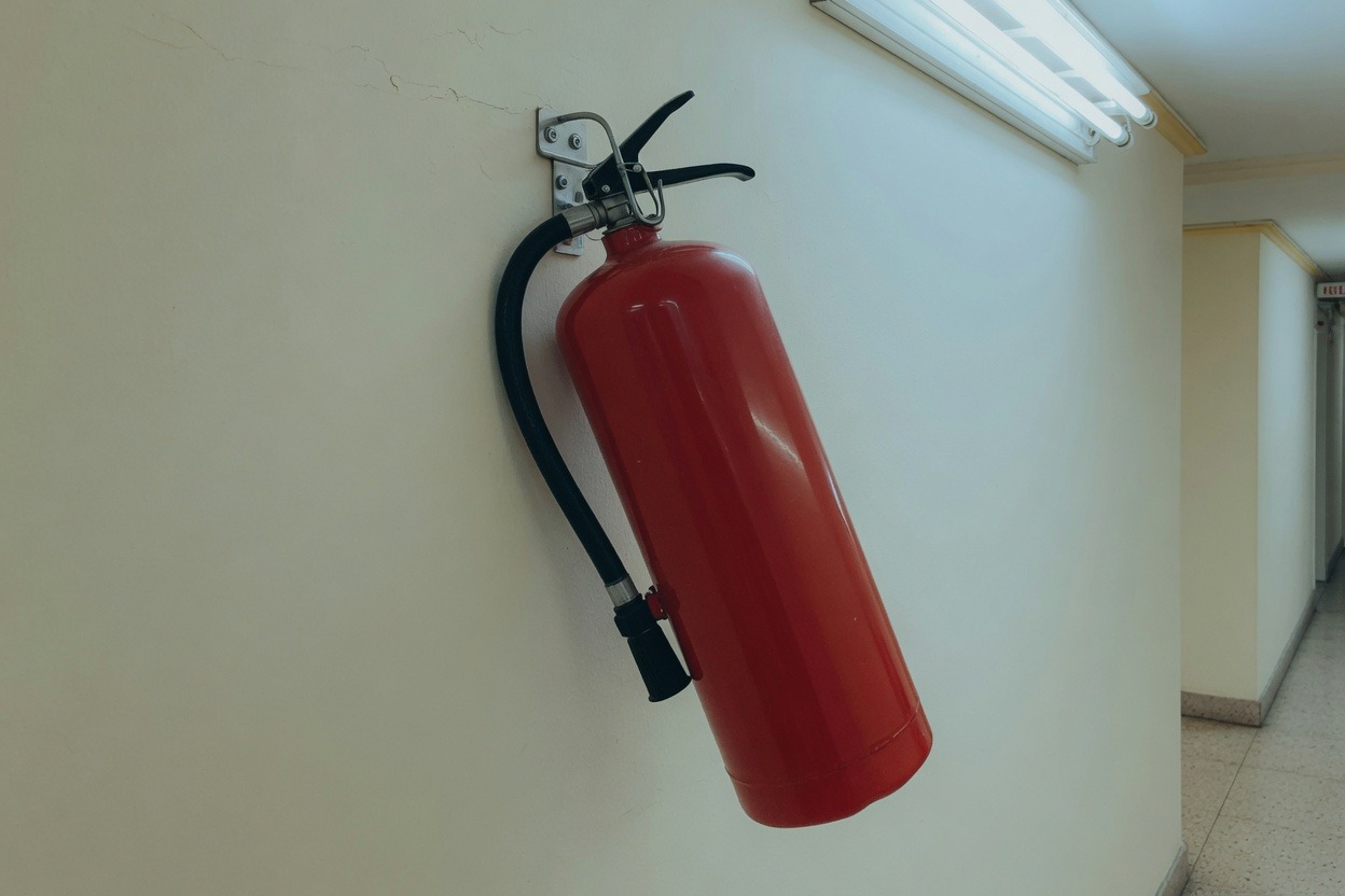 Red fire extinguisher hanging on a corridor wall hook