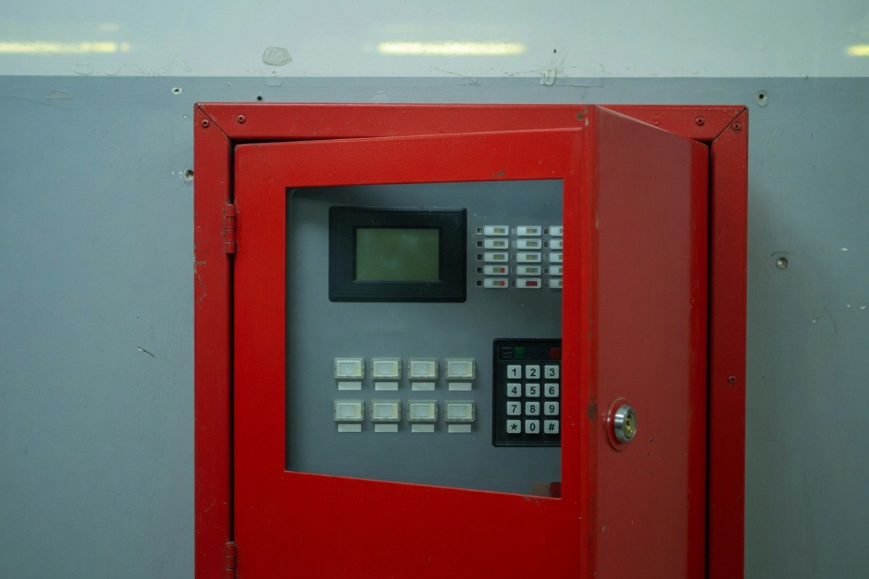Red addressable fire alarm control panel on a plant-room wall
