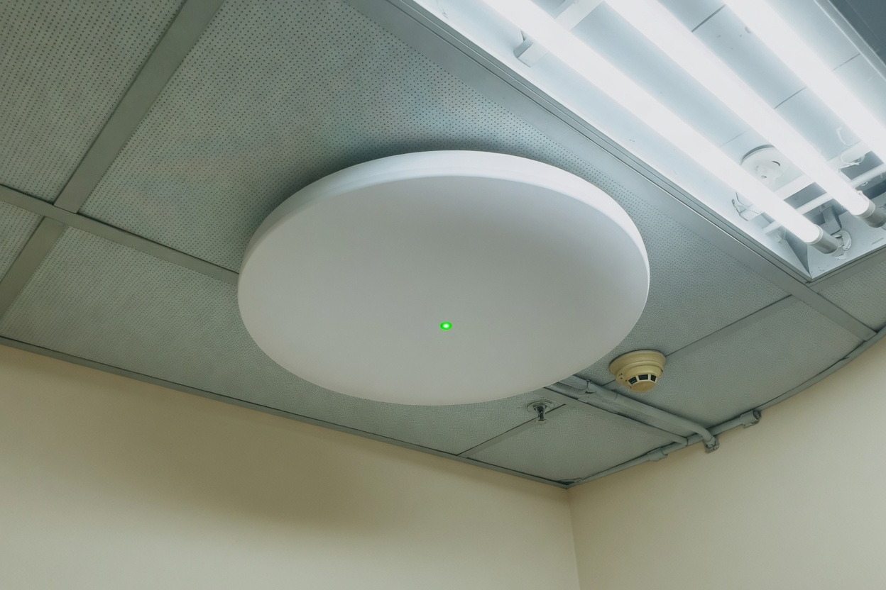 White circular ceiling access point in a Malaysian office corridor